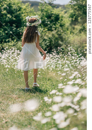 Daisy Wreath Girl Summer: Child strolls through daisy field during sunny summer day. Daisy Wreath Girl Summer: Child strolls through daisy field during sunny summer day. 128775567