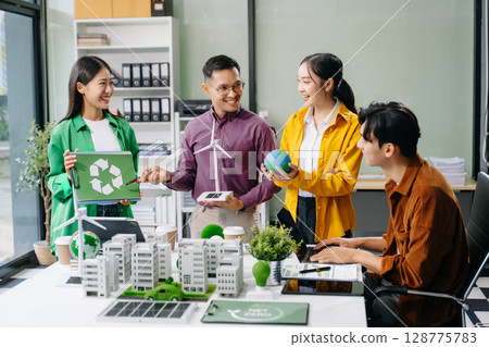 Group of diverse multiethnic businesspeople standing neare table looking at model of building from residential project. Green business company 128775783
