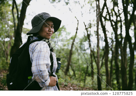 Young female traveler with backpack walking in national park or forest. recreation sport in nature. Female person bag, wave for hiking journey in woods. adventure in forest. trekking with backpack 128775825