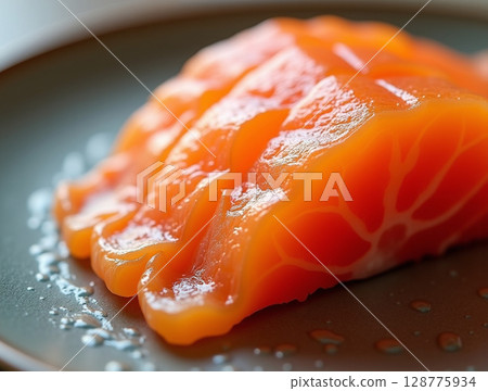 Diagonal Macro of Salmon Sashimi Showing Fat Marbling and Glossy Wet Textures on Translucent Orange Flesh 128775934