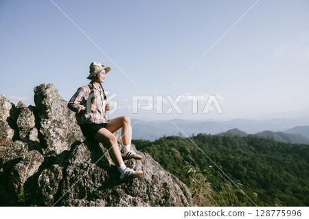 Woman hiker on top of mountain. Hiker with arms up on top of mountain successful young woman enjoying triumph. traveler exploring world. Hikers with backpacks relaxing. Sport and success concept. 128775996
