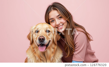 Young woman smiling with golden retriever against pink background, showcasing joyful bond 128776320