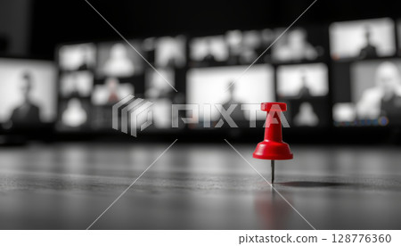 Closeup of red pushpin stands out against blurred background of multiple screens displaying people virtual meeting 128776360
