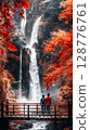 lover on wood bridge under a large blossom colorful changing color leaves and big waterfalls background 128776761