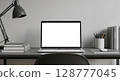 Modern workspace with laptop, lamp, and books on a dark gray desk. 128777045