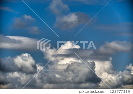 A vibrant display of clouds fills the clear blue sky, creating a beautiful scene. 128777319