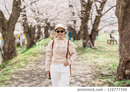 Woman tourist sightseeing Sakura Cherry Blossom in Spring. Happy traveler travel near Hinokinai River riverbank in Kakunodate town, Semboku District, Akita Prefecture, Japan. Landmark and Vacation Woman tourist sightseeing Sakura Cherry Blossom in Spring. Happy traveler travel near Hinokinai River riverbank in Kakunodate town, Semboku District, Akita Prefecture, Japan. Landmark and Vacation 128777399