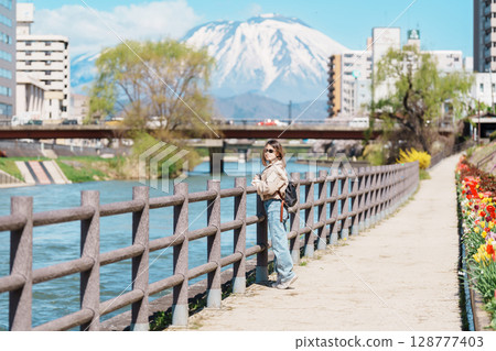 Woman tourist sightseeing Iwate mountain and Kitakami river with flowers in Spring, happy traveler travel in Morioka city, Iwate prefecture, Japan. famous Landmark Travel and Vacation destination Woman tourist sightseeing Iwate mountain and Kitakami river with flowers in Spring, happy traveler travel in Morioka city, Iwate prefecture, Japan. famous Landmark Travel and Vacation destination 128777403