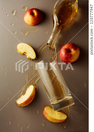 Apple juice is poured into a glass. Apple juice is poured into a glass. 128777947