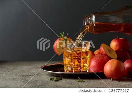 Apple kombucha is poured from a bottle into a glass. Apple kombucha is poured from a bottle into a glass. 128777957