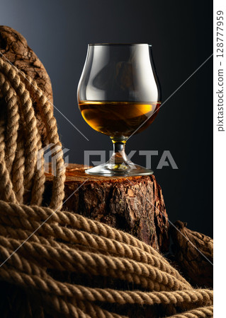 Brandy snifter and rope on a old stumb. Brandy snifter and rope on a old stumb. 128777959
