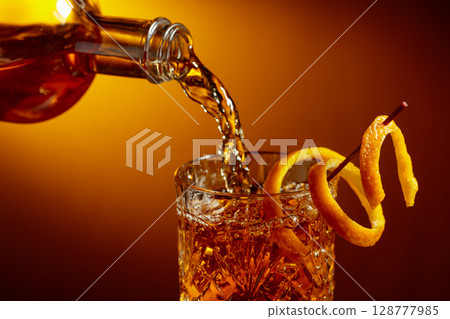 Whiskey or bourbon pouring into a crystal glass. 128777985