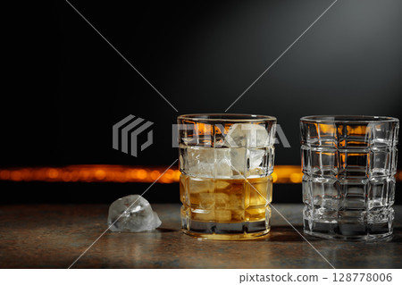 Whiskey with ice on a dark background. 128778006