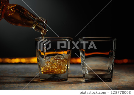 Whiskey is poured into a crystal glass. 128778008