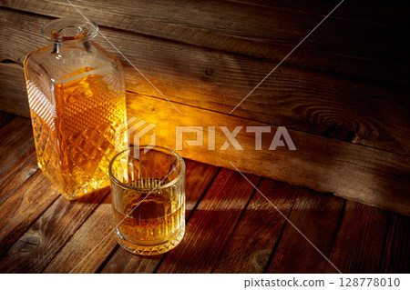 Elegant whiskey glass and decanter on a old wooden table. 128778010