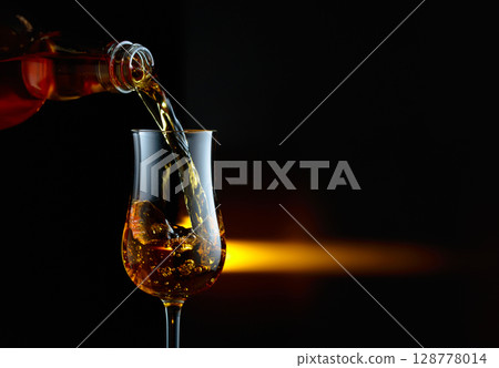 Bourbon being poured into a glass. Bourbon being poured into a glass. 128778014