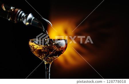 Rum being poured from a bottle into a glass. 128778018