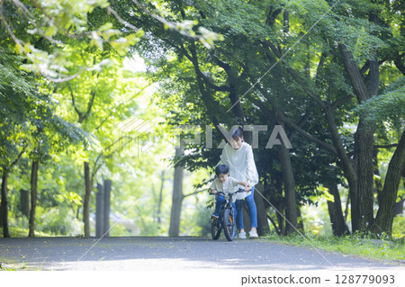 Parent and child practicing riding a bicycle 128779093