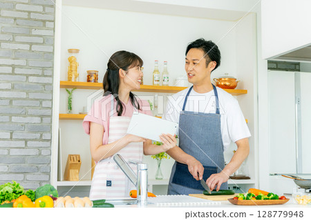 A couple cooking while checking a recipe on a tablet A couple cooking while checking a recipe on a tablet 128779948
