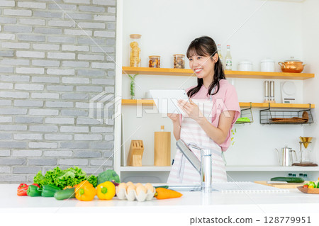 Young woman in kitchen with tablet 128779951