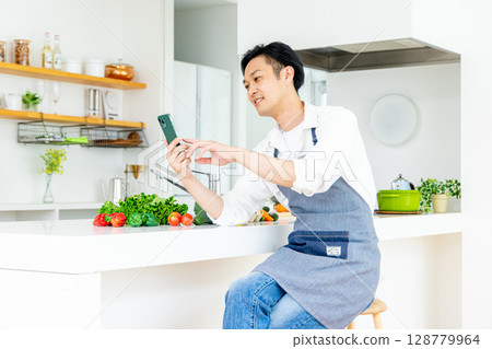 廚房裡使用智慧型手機的男人 128779964