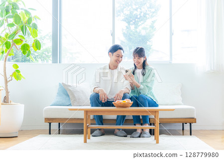 Young couple looking at a smartphone in the living room Young couple looking at a smartphone in the living room 128779980