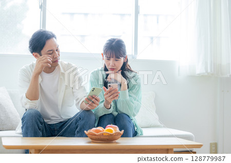 一對夫婦沮喪地看著他們的智慧型手機 128779987