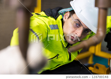 Technician man checking quality inspection of welding heads of robot arms automatic. Programming machinery welding robot in factory industry. Technician man checking quality inspection of welding heads of robot arms automatic. Programming machinery welding robot in factory industry. 128780148