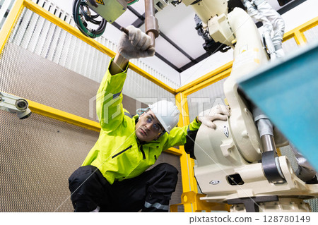 Technician man checking quality inspection of welding heads of robot arms automatic. Programming machinery welding robot in factory industry. 128780149