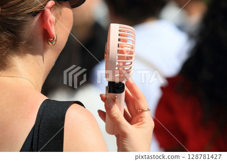 A woman walking with a handheld fan A woman walking with a handheld fan 128781427