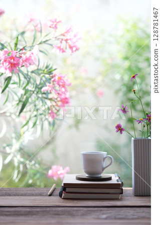 White coffee cup with notebook and pink flowers by the window 128781467