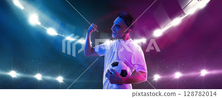 Male soccer player excited after game holding ball under 3D stadium lights Male soccer player excited after game holding ball under 3D stadium lights 128782014