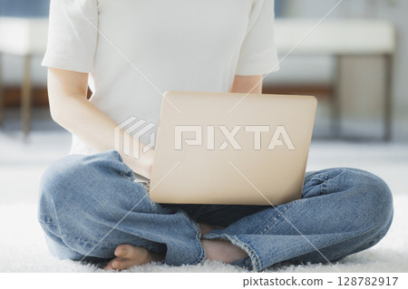 Young woman using a computer in the living room 128782917