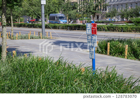 Multiple white and red utility signs displaying technical codes and measurements on a blue pole, crucial for urban infrastructure planning and public service management in a city 128783070