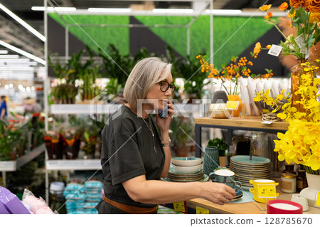 Mature woman engaged in shopping for home and garden products in a large retail store Mature woman engaged in shopping for home and garden products in a large retail store 128785670