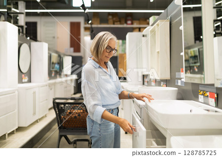 Woman selecting bathroom furniture in a home goods store while enjoying the shopping experience and 128785725