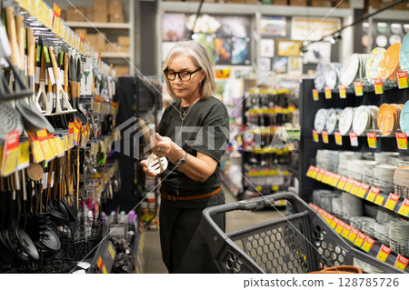 Commercial photography session in a home goods store featuring a middle-aged woman interacting with 128785726