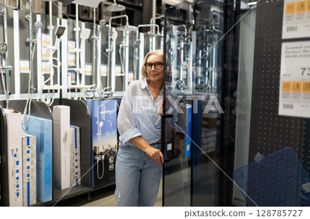 Middle-aged woman enjoys shopping experience in home improvement store exploring various departments 128785727