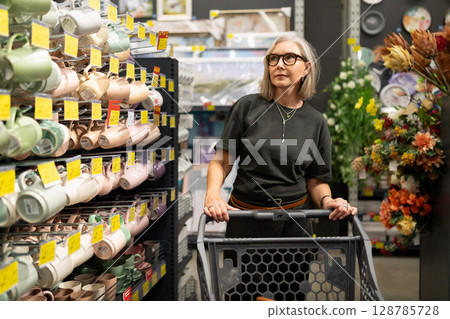 Woman shopping in a hypermarket while selecting home goods and decor items with genuine emotions 128785728