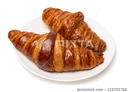 Two freshly baked classic delicious fresh organic croissants on white ceramic plate isolated on white background 128785780