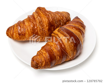 Two freshly baked classic delicious fresh organic croissants on white ceramic plate isolated on white background 128785782