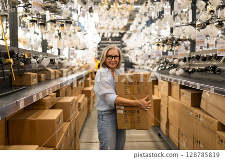 Middle-aged woman shopping for home improvement supplies in a busy retail store Middle-aged woman shopping for home improvement supplies in a busy retail store 128785819