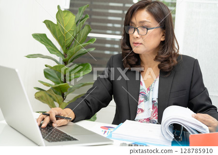 Asian accountant working and analyzing financial reports project accounting with chart graph and calculator in modern office, finance and business concept. 128785910