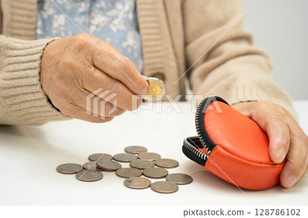 Asian elderly woman holding counting coin money in purse. Poverty, saving problem in retirement. Asian elderly woman holding counting coin money in purse. Poverty, saving problem in retirement. 128786102
