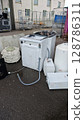 Discarded appliances awaiting recycling at an industrial site during daylight hours close to urban surroundings 128786311