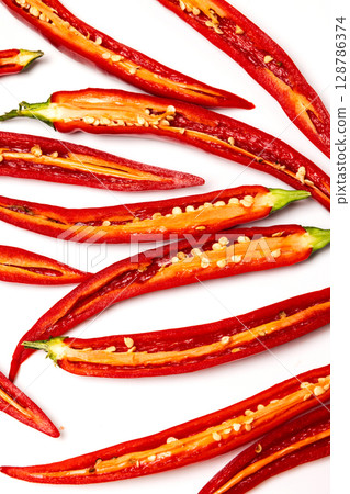 Sliced pods of red natural organic chili pepper on white background Sliced pods of red natural organic chili pepper on white background 128786374