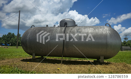 Large industrial propane tank installed outdoors on grass, designed for fuel storage and efficiency. The tank showcases durability and purpose for various industries and homes 128786559