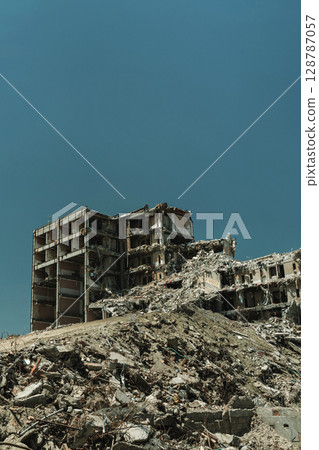destroyed high-rise apartment building surrounded by wreckage and rubble 128787057