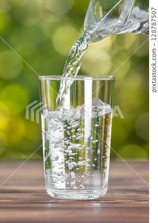 Drink water from jug pouring into glass on wooden table 128787507