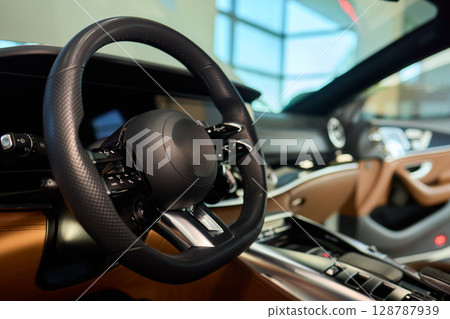 Closeup of a modern car steering wheel with control buttons for technology and convenience 128787939